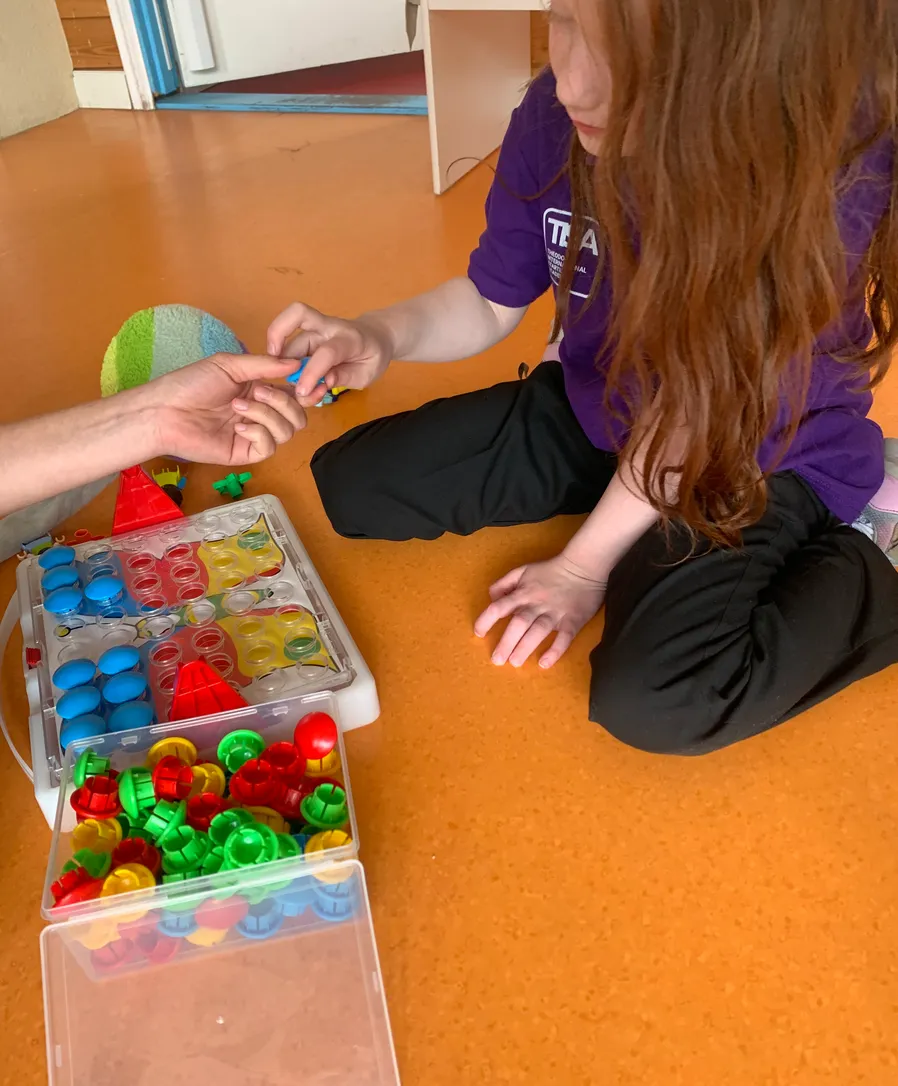 Student engaged in a sensory activity with a Care Group specialist at TISA Leiden