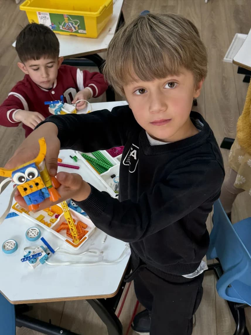 TISA student proudly showing off his robotics creation
