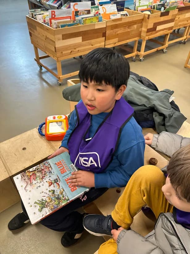 A young student in a purple TISA vest absorbed in a book