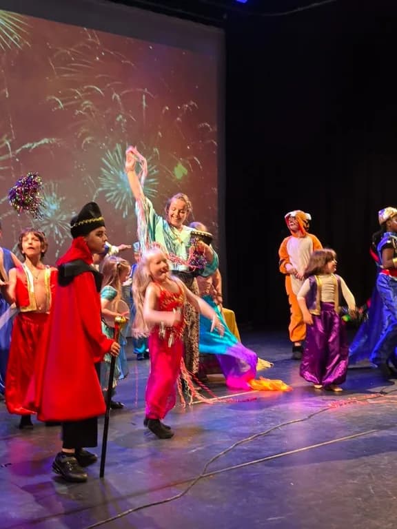 TISA students in colorful Aladdin-style costumes dancing on stage