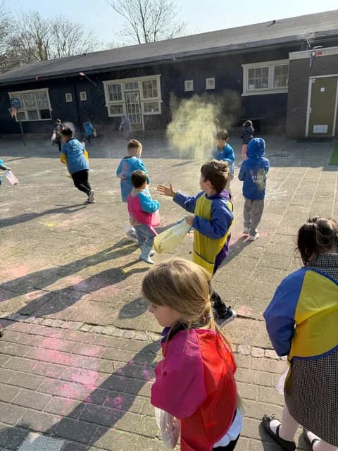 Students throwing colorful powder in the schoolyard during a Holi-style celebration